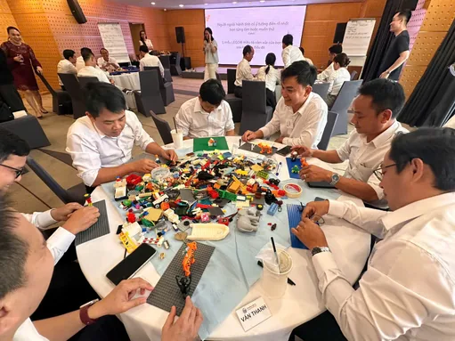 Executives building with LEGO bricks around a table in a workshop