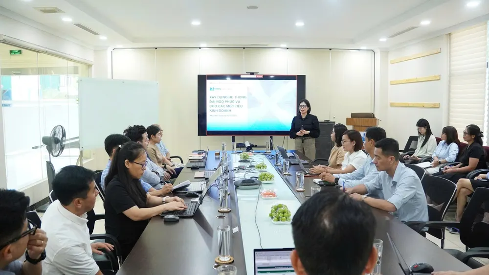 NSN workshop room: a large screen showing a slide on building a rewards system to serve business objectives, with participants around a long meeting table